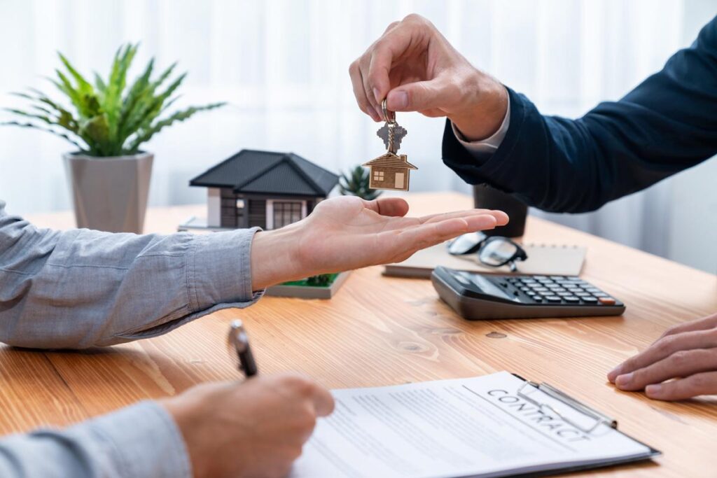 A person handing another person house keys while filling out a contract in El Paso, TX
