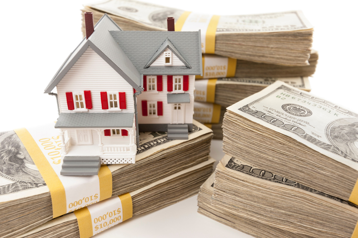 Stacks of $100 bills with a miniature house on top.